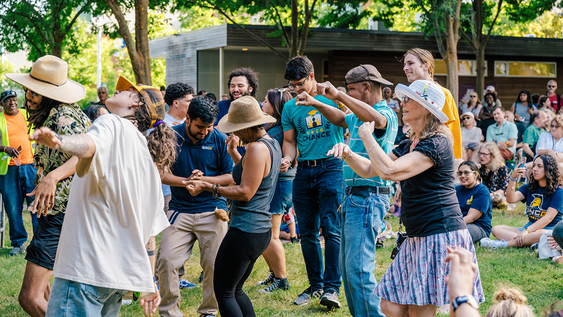 Crowd dances on a grassy lawn at the folk festival.