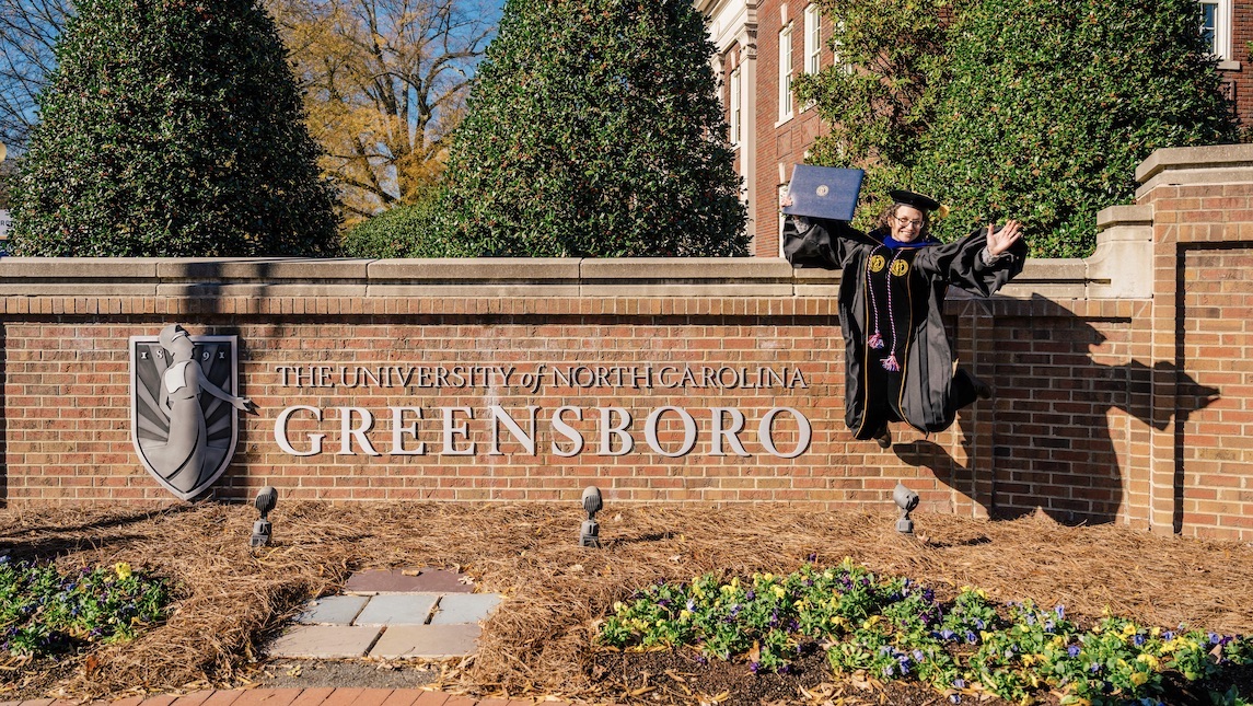 Kim Vogt jumping for joy after graduating with a PhD for School of Nursing.