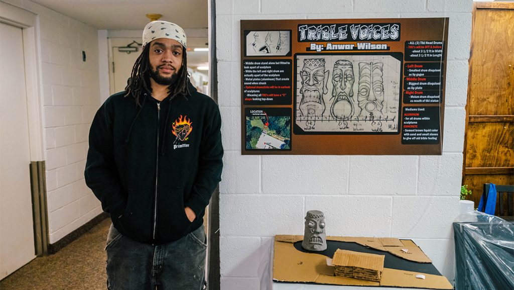 A UNCG student stands next to his model of a sculpture about movement.