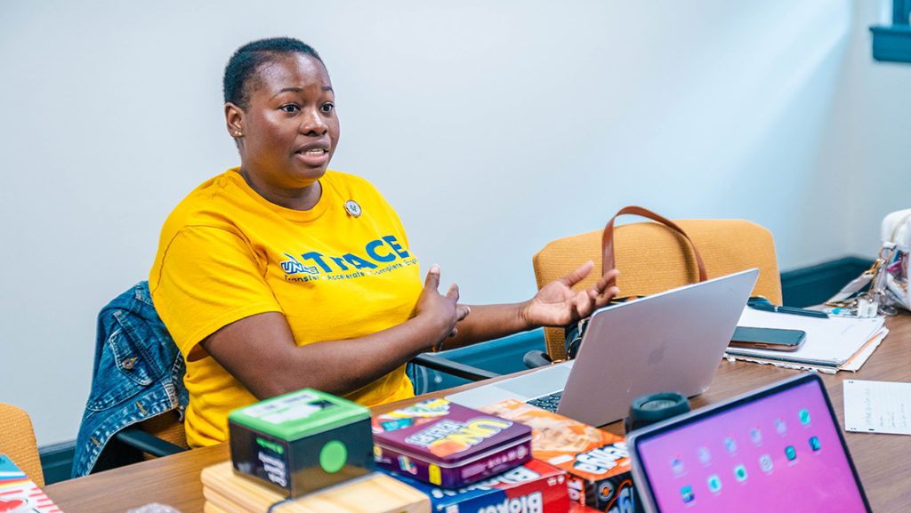 UNCG student Natalie Paul surrounded by board games on a table.