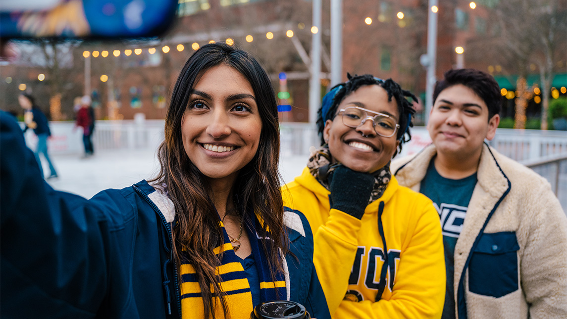 Three UNCG students pose for a selfie at a skating rink.