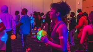 UNCG students play dodgeball under blacklight.