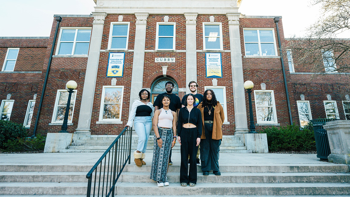 Group of students stand on the steps of the Curry building at UNCG.