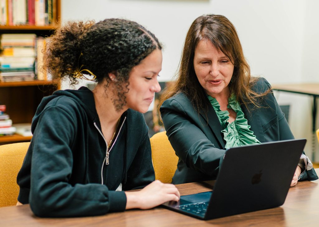 Student and professor look at a laptop together.