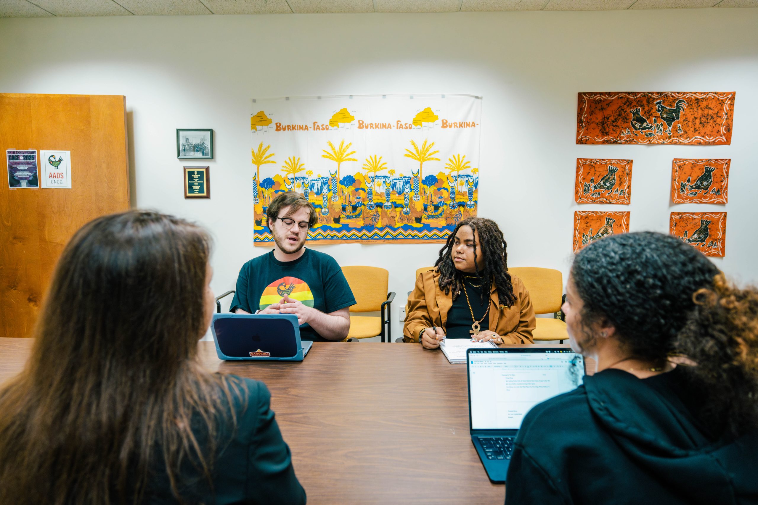 Group of students sit at a table together in the AADS library.