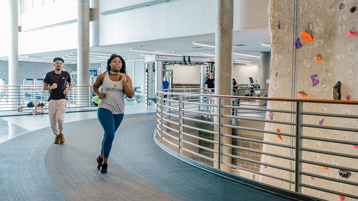 Two runners take a turn around the track at the UNCG Kaplan Center.